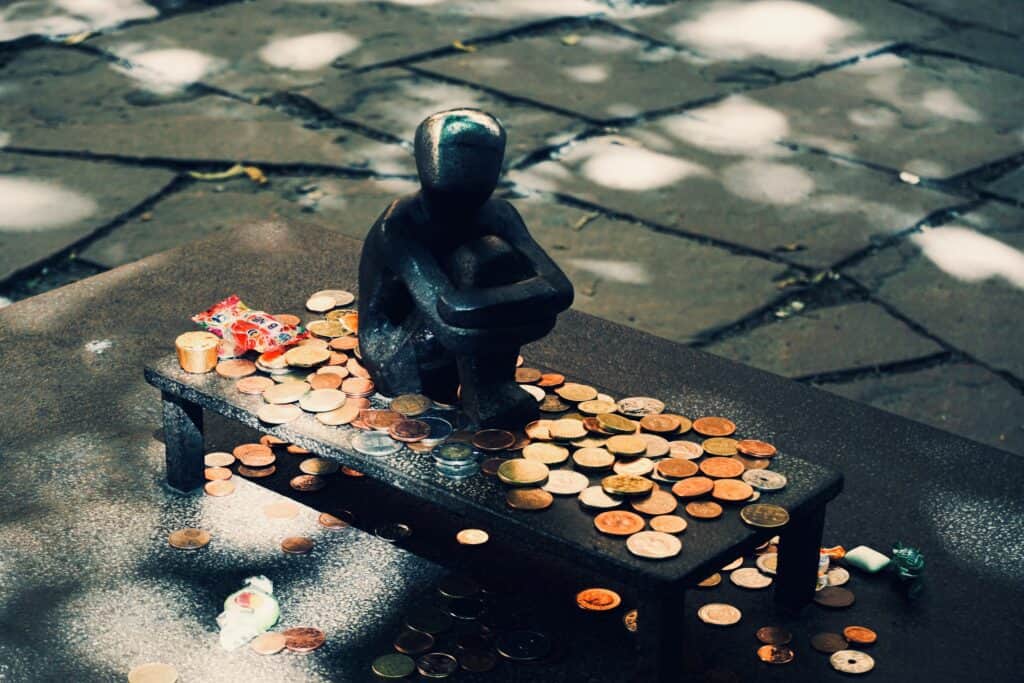 Statue of a small boy and coins surrounding it. Bribing to have babies is one population control strategy