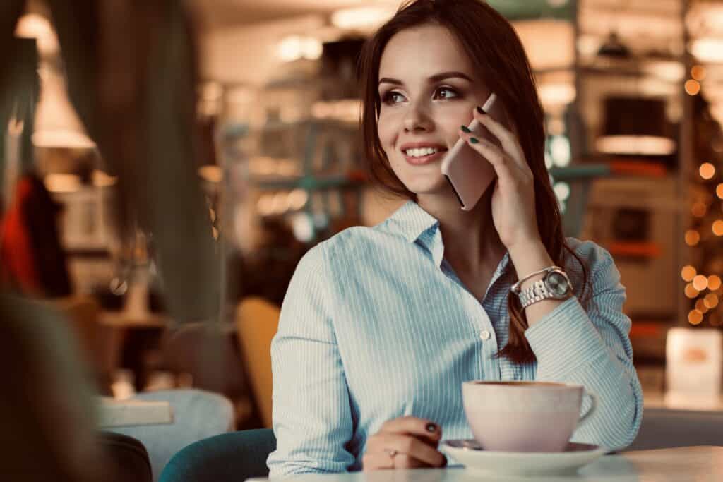 A woman holding a phone and smiling. Men mistakenly think if women gives them their phone numbers, they want to get laid with them.