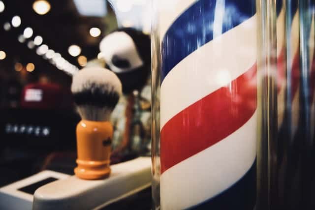 Barber pole with red, white, and blue stripes outside a barbershop